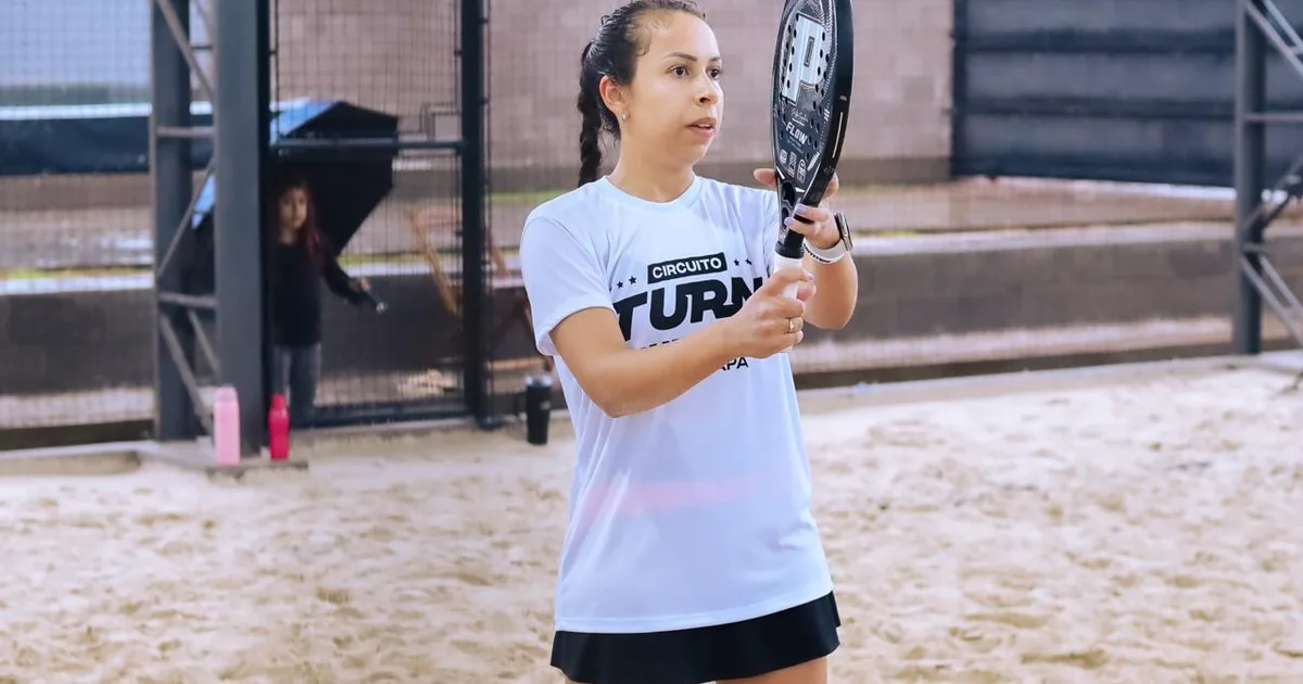 Geovana Kohut em partida de beach tennis segurando raquete na quadra de areia